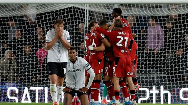 John Eustace, entrenador de Derby County, parado en el borde del campo durante un partido del Championship.