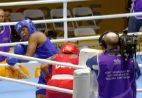 Lauren Price festeja después de una pelea con los cinturones de campeona mundial en el ring.